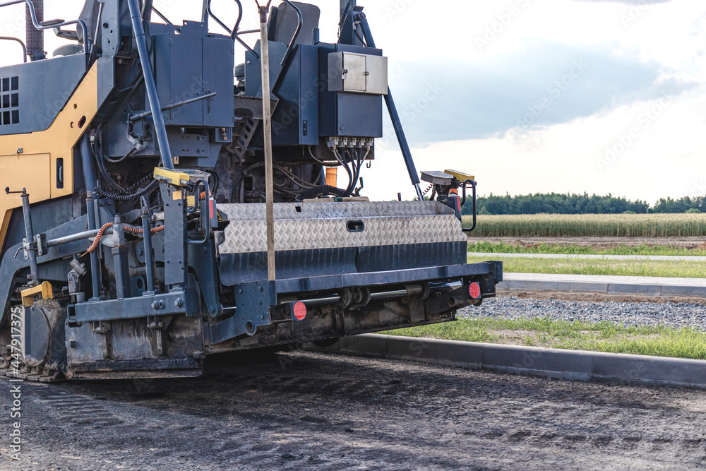 Asphalt paving equipment. Professional asphalt paver close-up. Construction of new roads and road junctions. Heavy construction industrial machinery.