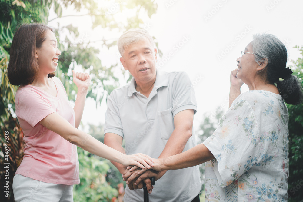Happy family walking together in the garden. Old elderly using a walking stick to help walk balance. Concept of Love and care of the family And health insurance for family Happy family walking together in the garden. Old elderly using a walking stick to help walk balance. Concept of Love and care of the family And health insurance for family