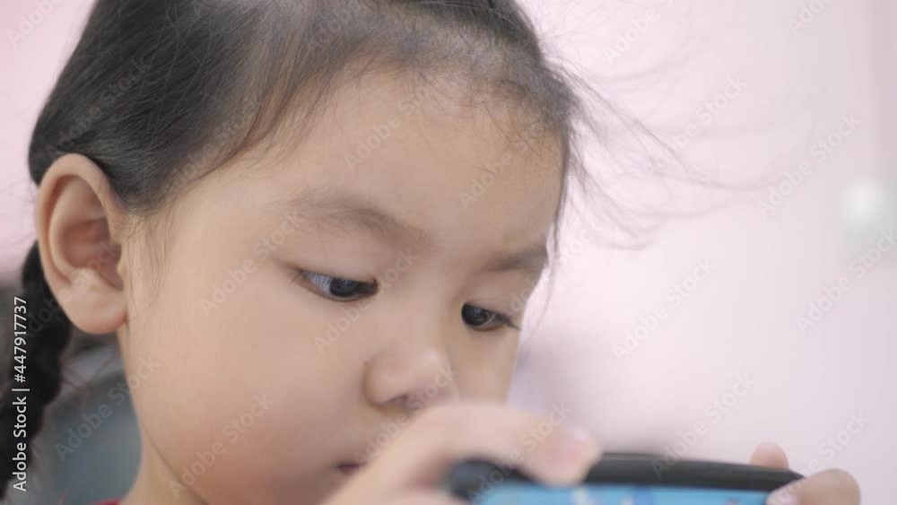 Slow motion scenes of Asian girls, ages 4-5, are playing on the phone intently. Slow motion scenes of Asian girls, ages 4-5, are playing on the phone intently.