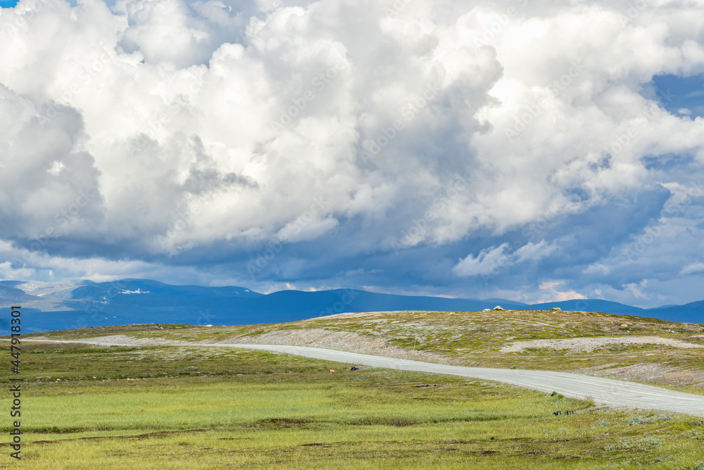 Dirt road in high country landscape with a cloudscape in the sky Dirt road in high country landscape with a cloudscape in the sky