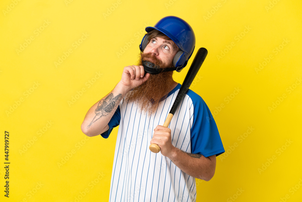 Redhead baseball player man with helmet and bat isolated on yellow background and looking up