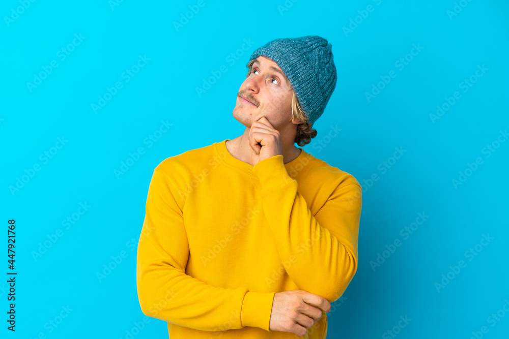 Handsome blonde man isolated on blue background and looking up Handsome blonde man isolated on blue background and looking up