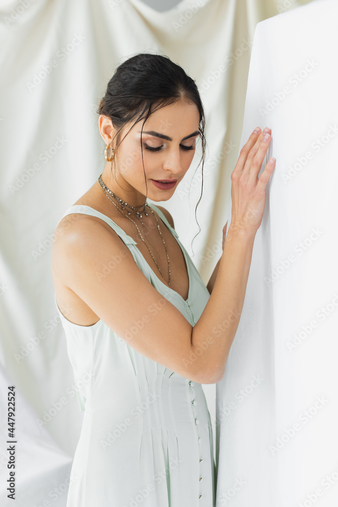 brunette woman in dress looking down while posing on white brunette woman in dress looking down while posing on white