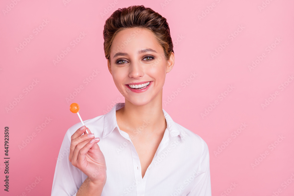 Photo of young happy cheerful positive woman smile good mood attractive eat lollipop isolated on pink color background Photo of young happy cheerful positive woman smile good mood attractive eat lollipop isolated on pink color background