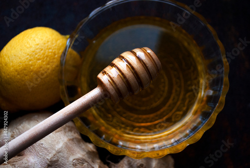 Honey ladle in a bowl of liquid honey. Honey, lemon and ginger mixture for boosting immunity.