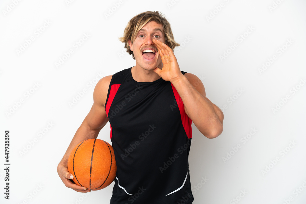 Young blonde man holding a ball of basketball isolated on white background shouting with mouth wide open Young blonde man holding a ball of basketball isolated on white background shouting with mouth wide open