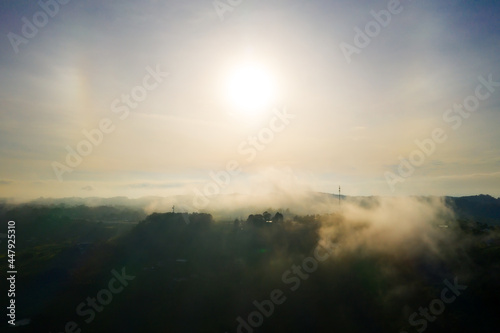 Aerial view, clouds above mountain top. Panoramic scene. High peak wonderful in morning sunrise. Shot from drone.