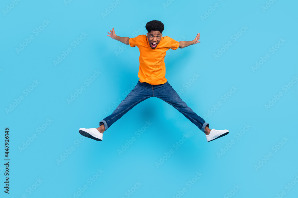 Obraz premium Full size photo of hooray brunet young guy jump yell wear orange t-shirt jeans isolated on blue color background