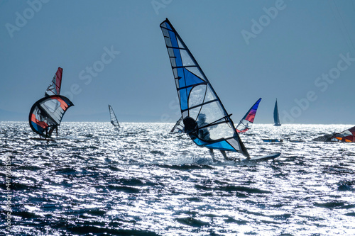 SILHOUETTE: Scenic shot of a group of windsurfers riding waves at golden sunset. © helivideo