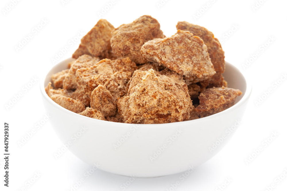 Close-Up of sugarcane jaggery piece in white ceramic bowl over white background Close-Up of sugarcane jaggery piece in white ceramic bowl over white background