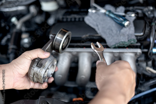 Wrench in the hand of a technician for take off Belt Tension Pulley old part car engine Replacement of spare parts in engine room photo