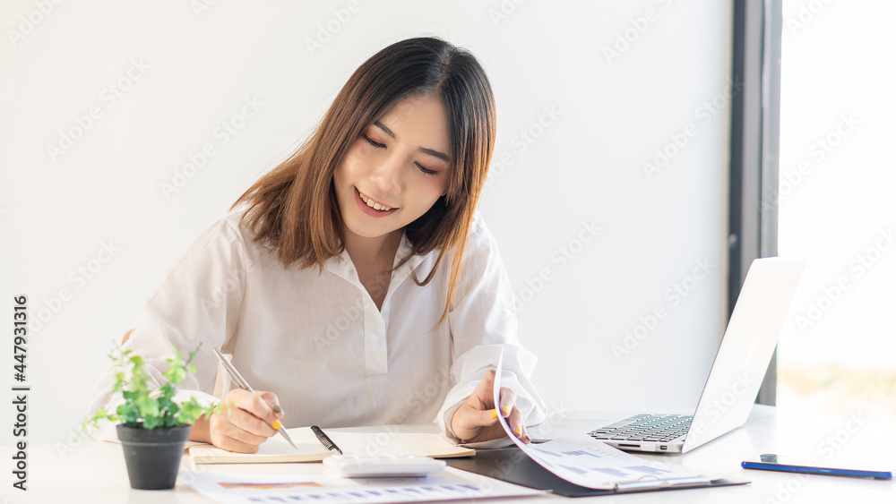 Young Asian businesswoman working on laptop and analyzing financial accounting graphs in home office Young Asian businesswoman working on laptop and analyzing financial accounting graphs in home office