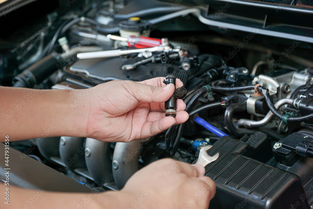 Technician Removing the petrol engine injector in engine room maintenance concept Technician Removing the petrol engine injector in engine room maintenance concept