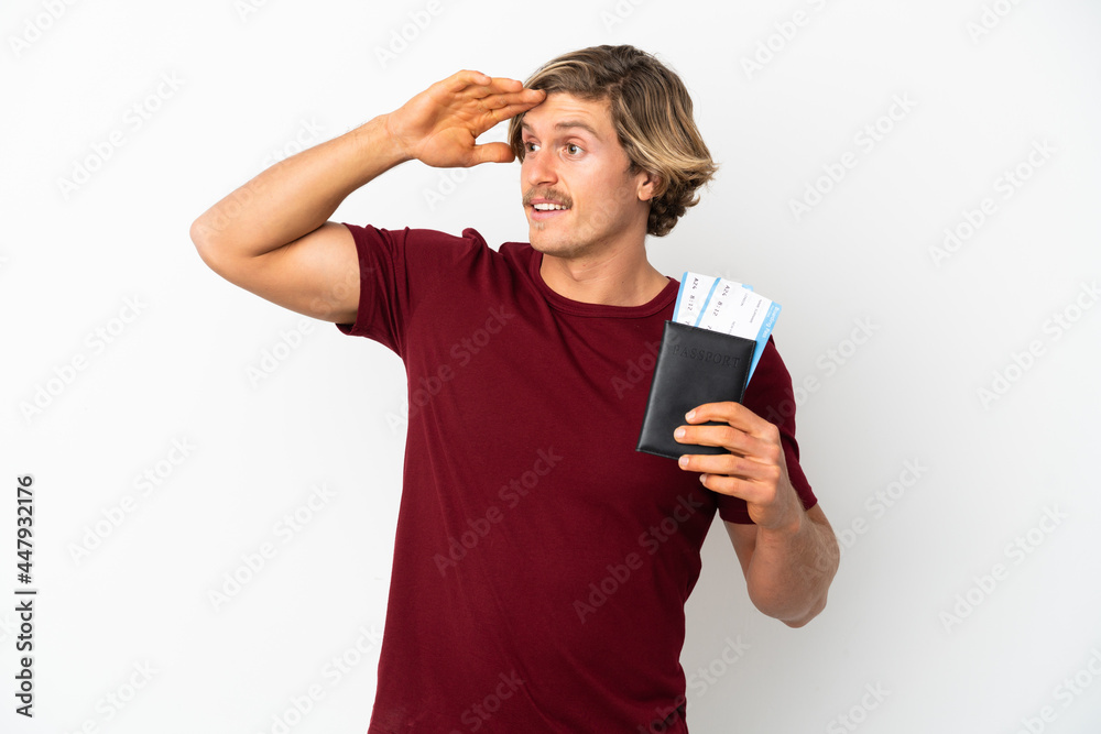 Young blonde man isolated on white background in vacation with passport and plane tickets while looking something in the distance Young blonde man isolated on white background in vacation with passport and plane tickets while looking something in the distance