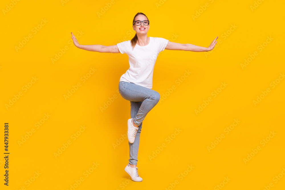 Full length photo of happy positive young charming woman hold hands wings smile isolated on yellow color background