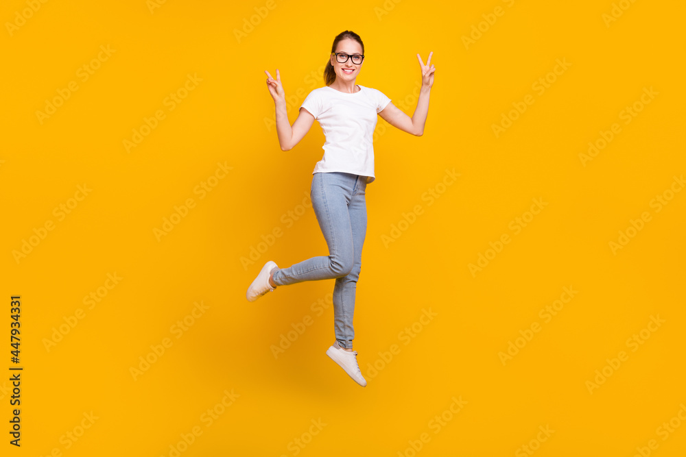 Full length photo of happy enjoy positive woman jump up make v-signs isolated on yellow color background