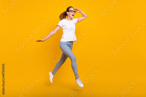 Full length photo of happy amazed brown haired woman jump wear casual clothes look empty space jump run isolated on yellow color background