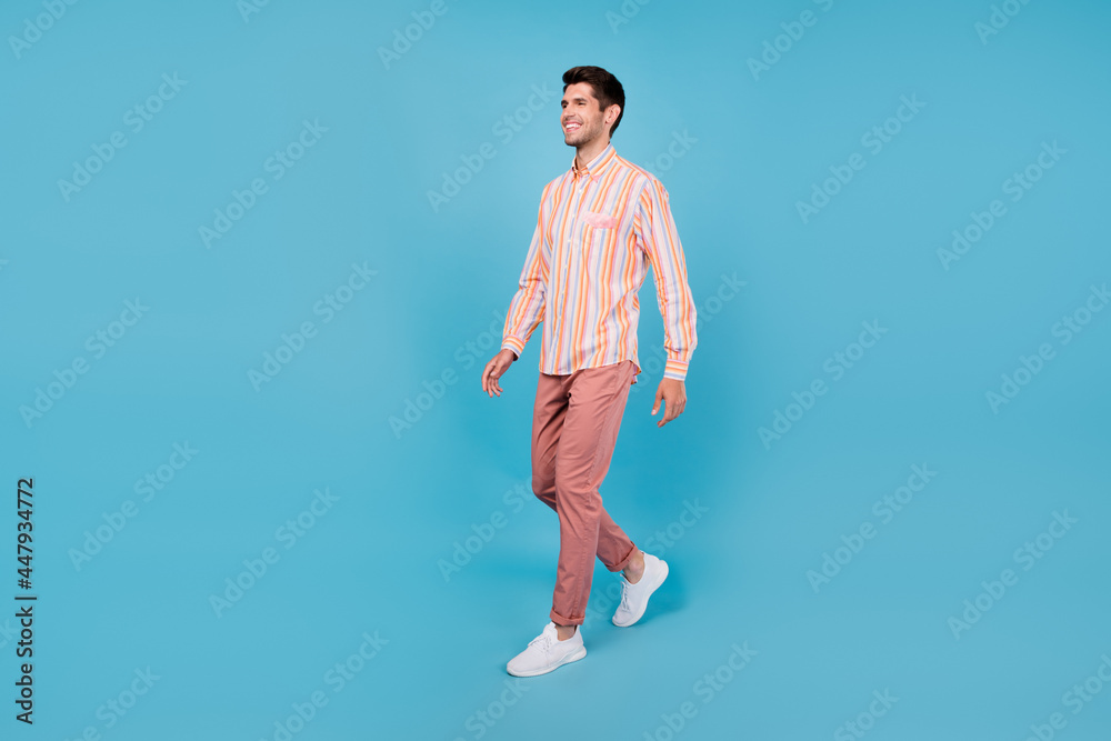 Full length profile side photo of young guy happy positive smile go walk meeting isolated over blue color background Full length profile side photo of young guy happy positive smile go walk meeting isolated over blue color background