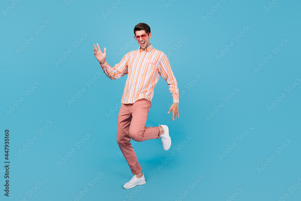 Full size photo of young man happy positive smile dance hipster sunglass isolated over blue color background