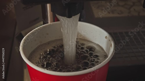 Pouring soft drink soda cola into the paper cup using machine