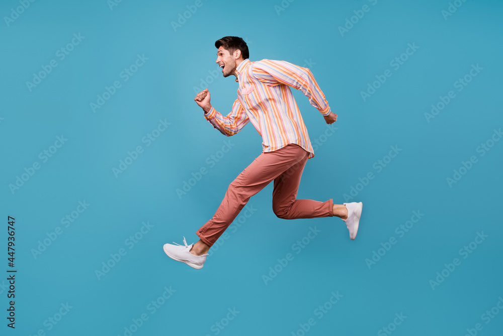 Full size profile side photo of young man happy positive smile jump run hurry sale isolated over blue color background