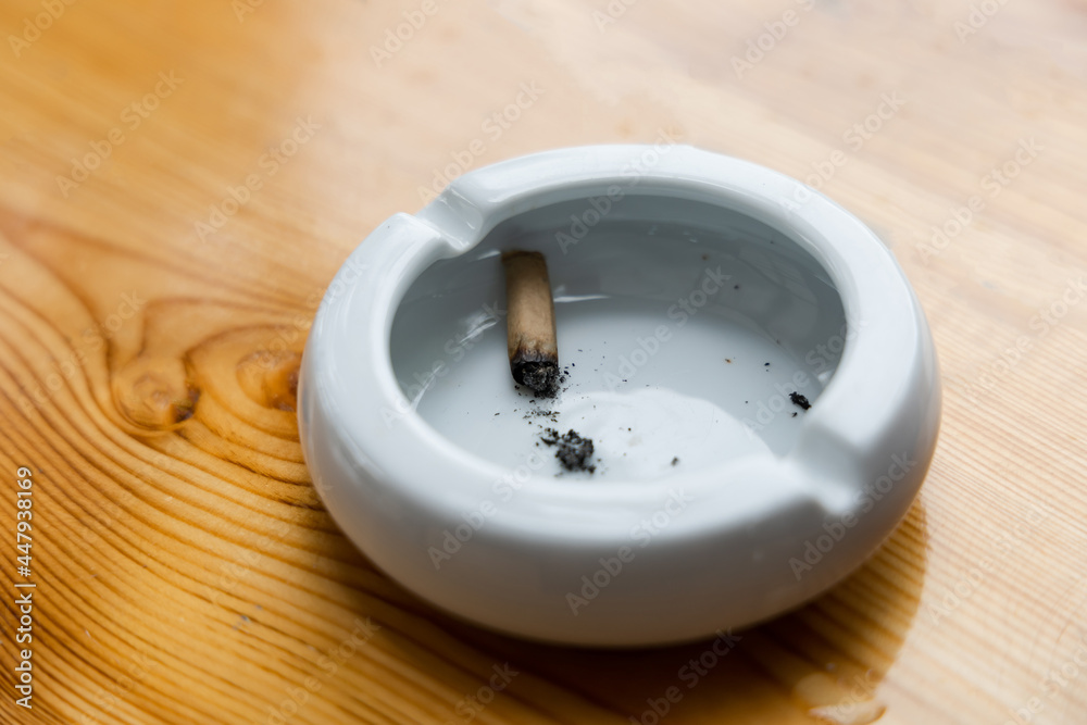 Cigarette stubs and ash in a glass ashtray on wooden table Cigarette stubs and ash in a glass ashtray on wooden table