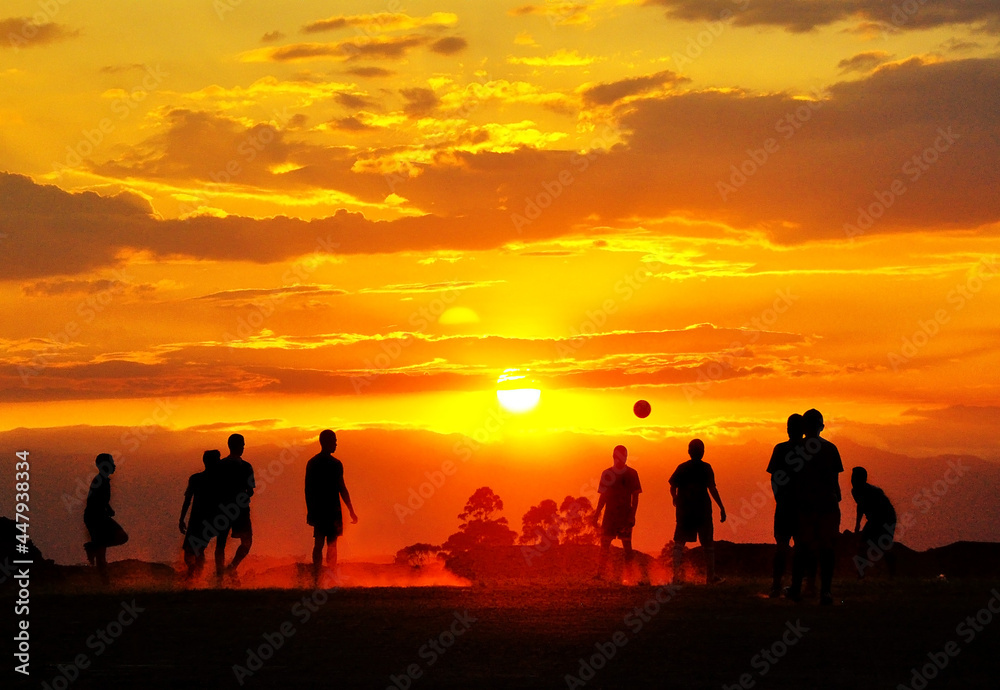 Silhouettes of unrecognizable children playing soccer at sunset Silhouettes of unrecognizable children playing soccer at sunset