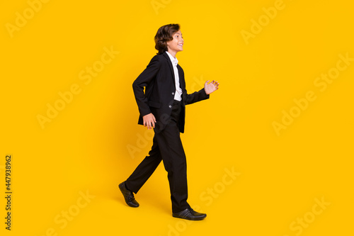 Profile photo of positive small boy enjoy promenade wear black uniform footwear isolated yellow color background