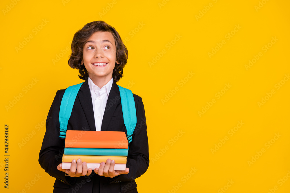 Photo of dreamer schoolboy hold stack book look empty space wear bag black uniform isolated yellow color background Photo of dreamer schoolboy hold stack book look empty space wear bag black uniform isolated yellow color background
