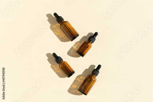 Bottles of dark amber glass with essential, lotion, serum on a beige background. Natural SPA organic cosmetic. Layout of the beauty salon branding. Flat lay, top view.