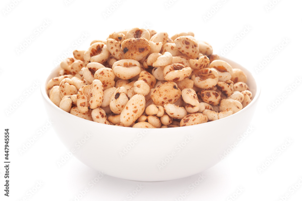 Close-up of dry organic puffed wheat in a white ceramic bowl over white background. Close-up of dry organic puffed wheat in a white ceramic bowl over white background.