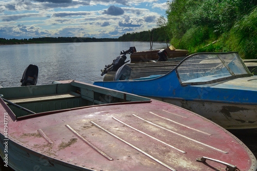 Boats on the banks of the river. Beautiful landscape by the river. The clouds are reflected in the water.
