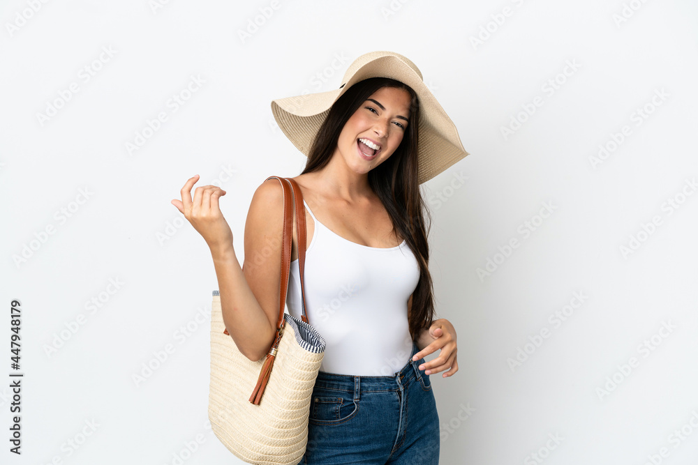 Young Brazilian woman with Pamela holding a beach bag isolated on white background making guitar gesture Young Brazilian woman with Pamela holding a beach bag isolated on white background making guitar gesture