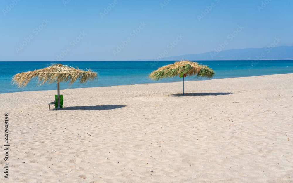 Two beach umbrela on sandy beach, mediterranean sea, Calabria Italy.
