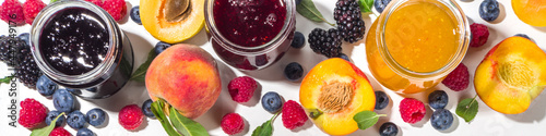 Assortment of summer seasonal berry and fruits jams in small jars, homemade preserving concept, marmalades or confitures with fresh berries on white background copy space photo