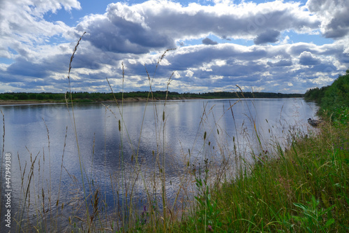 On the river bank. The clouds are reflected in the water.
