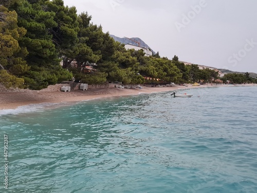 Croatian beach of Tucepi in the evening. Beautiful landscape with shoreline of Makarska Riviera and Adriatic Sea in Croatia on a cloudy summer day. Seaside view with fresh air from pine trees.