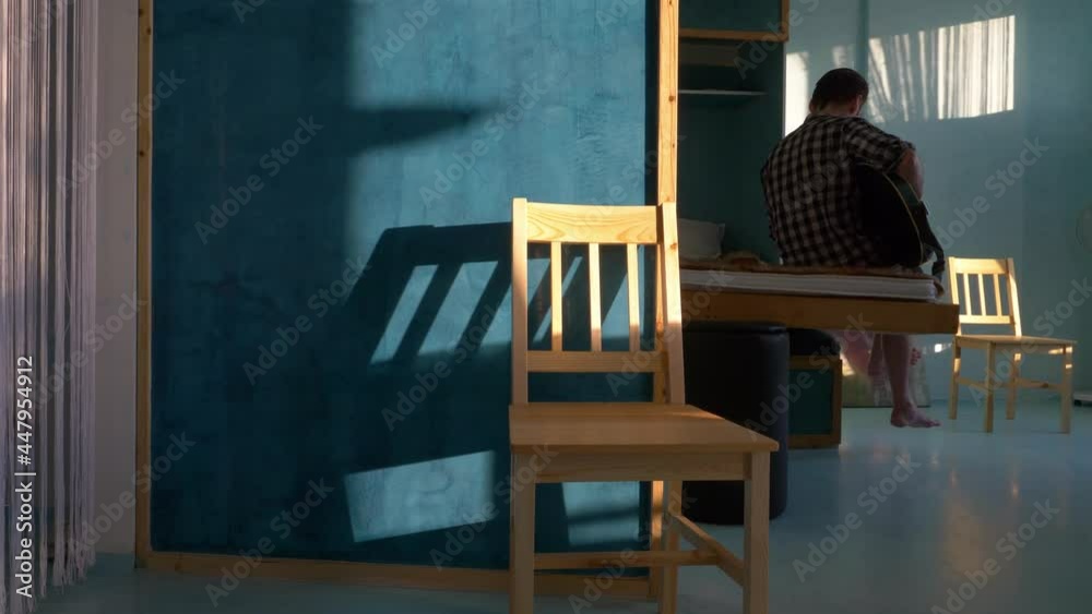 sunlit room in modern apartment, lockdown self isolation concept, man playing the guitar at home, staying home, beautiful light interior