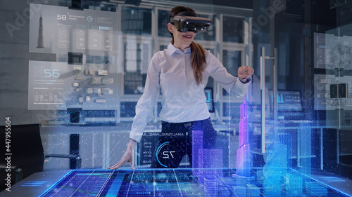 Professional Female Architect wearing Augmented Reality Glasses makes gestures and redesigns 3D City Model. High Tech Office use Virtual Reality Holographic Modeling Software Application. © Iokanan Pro