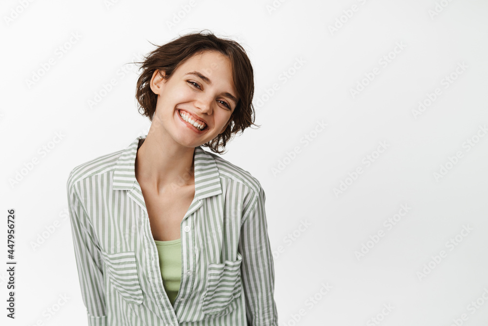 Portrait of beautiful brunette woman, girl smiling white teeth and looking happy, posing tenderly, standing in shirt over white background Portrait of beautiful brunette woman, girl smiling white teeth and looking happy, posing tenderly, standing in shirt over white background