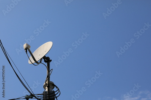 青空をバックに立つ衛星放送のパラボラアンテナ