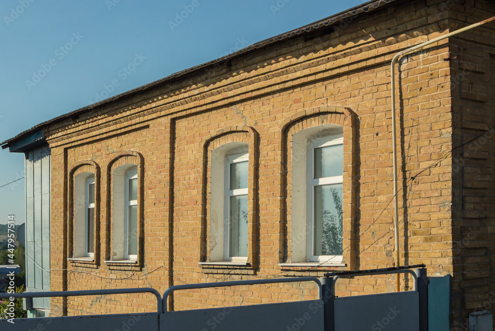 Facade of ancient brick house with new plastic windows