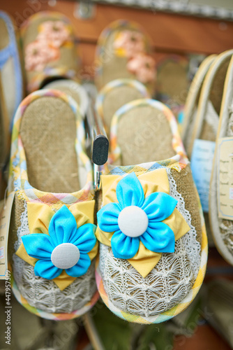 Home slippers decorated with blue and yellow fabric flowers and white knitted fabric