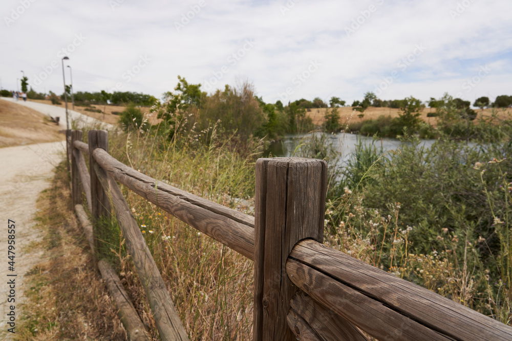 Brown wooden fence with a pond in the background on a park path