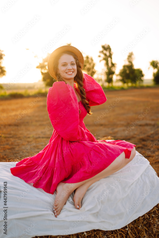 Beautiful curly woman in hat and clothes posing near hay bales in the countryside at sunset. Fashion concept. Nature, vacation, relax and lifestyle. Beautiful curly woman in hat and clothes posing near hay bales in the countryside at sunset. Fashion concept. Nature, vacation, relax and lifestyle.