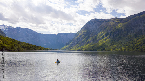 Aerial shot of kayakers on the lake, mother and son paddling toward mountains