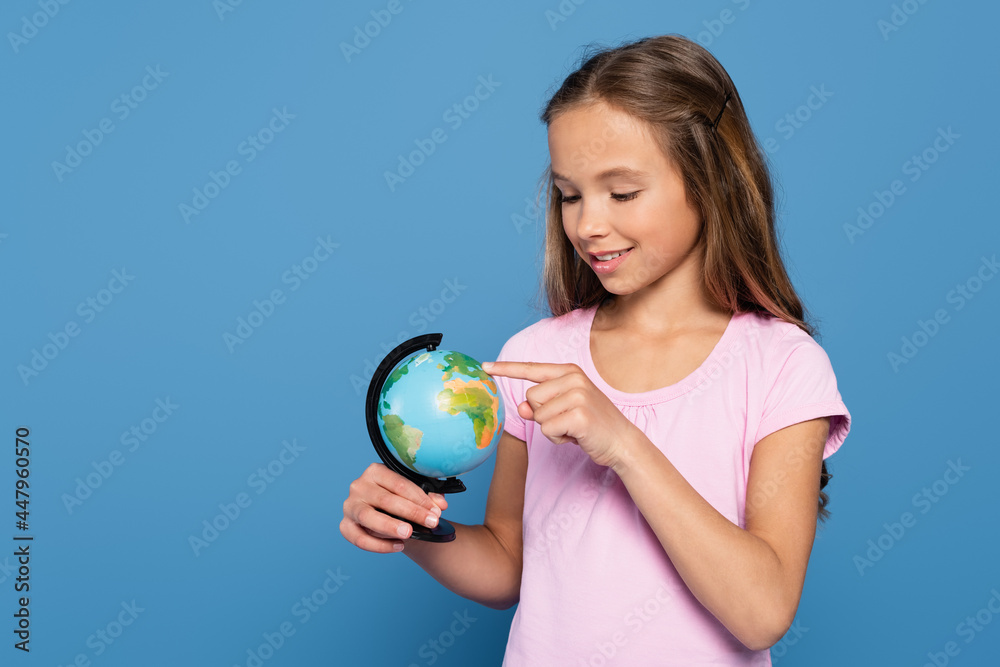 Cheerful child pointing at globe isolated on blue Cheerful child pointing at globe isolated on blue