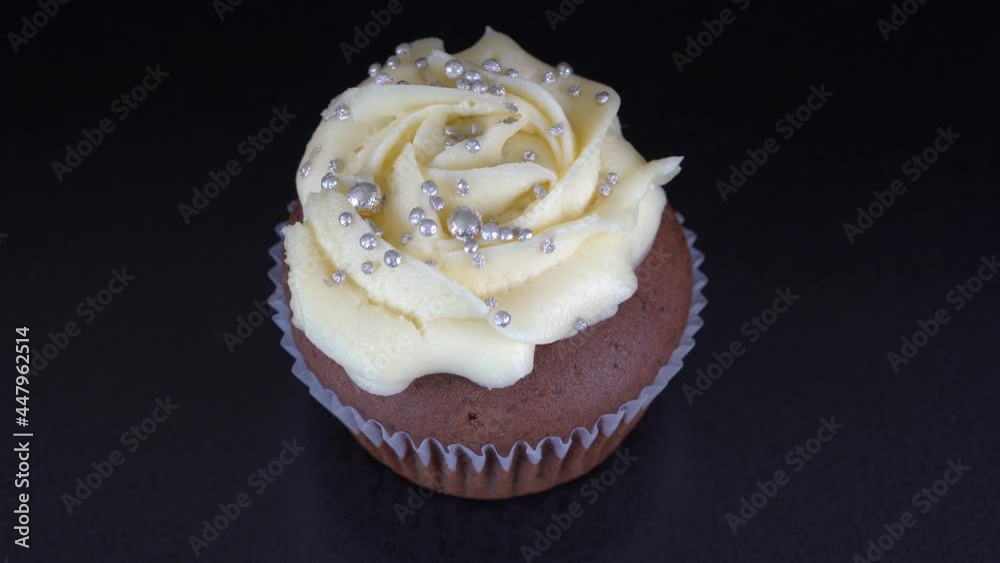 Fragrant, vanilla cupcake with berry filling and honey cream cheese on black background, close up, rotates Fragrant, vanilla cupcake with berry filling and honey cream cheese on black background, close up, rotates