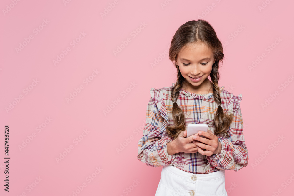 smiling girl in checkered blouse messaging on smartphone isolated on pink smiling girl in checkered blouse messaging on smartphone isolated on pink