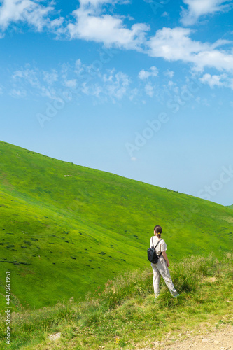 Girl traveler with a backpack resting in nature. The tourist looks at the panorama of the mountains. Mountain beautiful landscape © Виталий Борковский